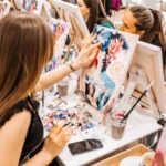 Young women paint with brushes on easels in guided art class